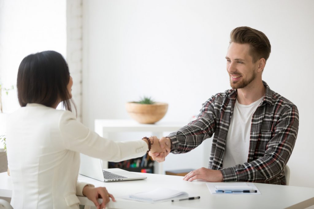 smiling millennial partners handshaking in office thanking for successful teamwork 1